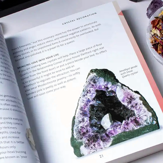An open book spread showing a crystal geode photo and text about crystal decoration, styled on a white surface with dried flowers, a candle, and crystals around it.